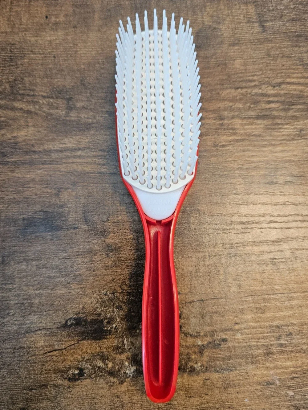 Vintage 1970s hair brush with a red handle and flexible white bristles
